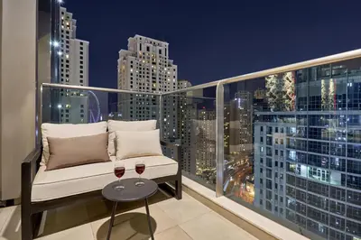 a balcony with a couch and two glasses of wine at Stylish 1BR Apartment with Marina View, Balcony, Pool & Gym Access in Dubai