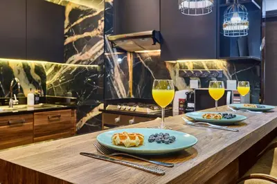 a kitchen with two glasses of wine and food on a counter at Stylish 1BR Apartment with Marina View, Balcony, Pool & Gym Access in Dubai