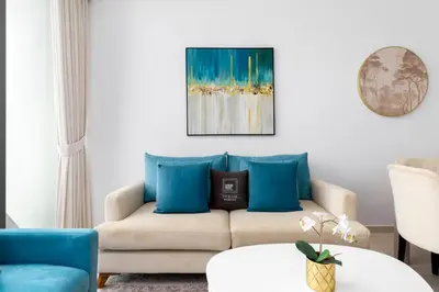 a living room with a couch with blue pillows at Maison Privee - Elegant Palm Retreat with Iconic Sea & Marina Vws in Dubai