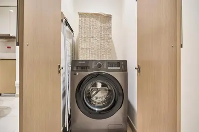 a washer and dryer in a laundry room at Luxury 2BR with Balcony, Burj Khalifa View & LED Night Show Downtown in Dubai