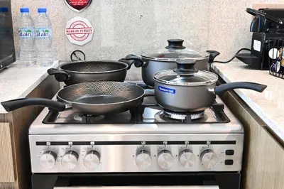 a stove with three pots and pans on it at CH Cozy & Luxury 1BR Apt in the Heart of Downtown in Dubai