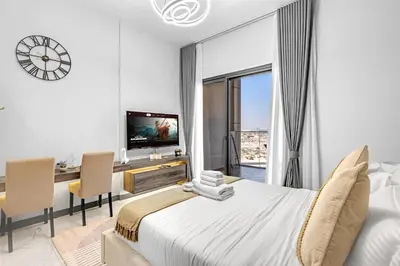 a bedroom with a bed and a desk and a tv at Classy Studio At Rukan in Dubai