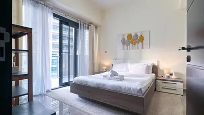 a bedroom with a bed and a large window at Modern 1BR in Merano, Near Downtown & Burj Khalifa - 14AB07 in Dubai