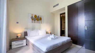 a bedroom with a large white bed with a night stand at Modern 1BR in Merano, Near Downtown & Burj Khalifa - 14AB07 in Dubai