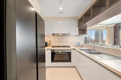 a kitchen with white cabinets and a stainless steel refrigerator at Luxury 4BR with full Burj Khalifa and Fountain View - 5Min to Dubai Mall in Dubai