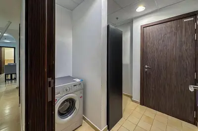 a laundry room with a washing machine and a wooden door at 2 Bedroom Apts in JBR Shams 1 by Luxaura in Dubai