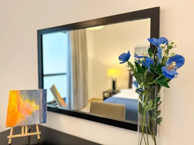 a vase of blue flowers on a counter in front of a mirror at 2 Bedroom Apts in JBR Shams 1 by Luxaura in Dubai