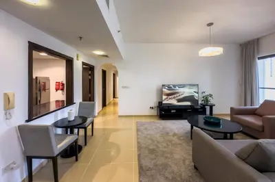 a living room with a couch and tables and a tv at 2 Bedroom Apts in JBR Shams 1 by Luxaura in Dubai