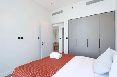 a white bedroom with a large bed and white cabinets at Chic 1B by Dubai Canal Marasi Drive with Pool, Gym in Dubai