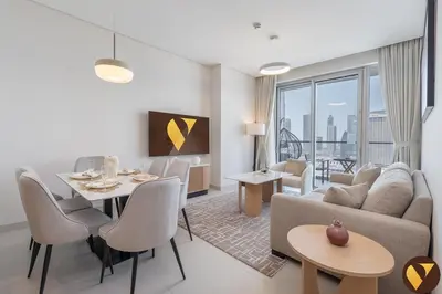 a living room with a couch and a table at Vogue Downtown Vida Dubai Mall, Direct Access to Dubai Mall via Climate Controlled bridge, Two Bedroom Apartment with Full Burj Khalifa View from Balcony and Access to all Amenities in Dubai