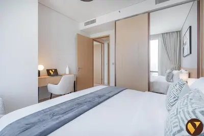 a hotel room with a large bed and a desk at Vogue Downtown Vida Dubai Mall, Direct Access to Dubai Mall via Climate Controlled bridge, Two Bedroom Apartment with Full Burj Khalifa View from Balcony and Access to all Amenities in Dubai
