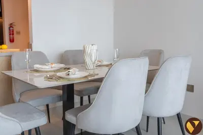 a dining room table with white chairs and a white table at Vogue Downtown Vida Dubai Mall, Direct Access to Dubai Mall via Climate Controlled bridge, Two Bedroom Apartment with Full Burj Khalifa View from Balcony and Access to all Amenities in Dubai