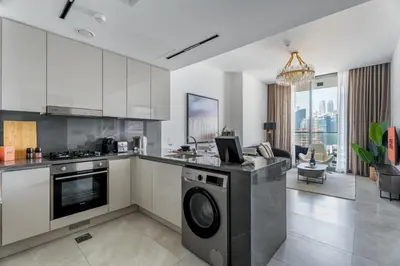 a kitchen with a washer and dryer next to a living room at GuestReady - Dubai Skyline & Canal View | 1 BHK in Dubai