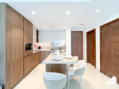 a kitchen with a table and white chairs at Luxurious 1BR with Balcony & Premium Stay in Downtown in Dubai