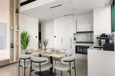 a white kitchen with a table and chairs at Private Pool Retreat Chic 2BR Sleeps 8 in Dubai