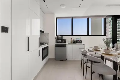 a kitchen with white cabinets and a table and chairs at Private Pool Retreat Chic 2BR Sleeps 8 in Dubai