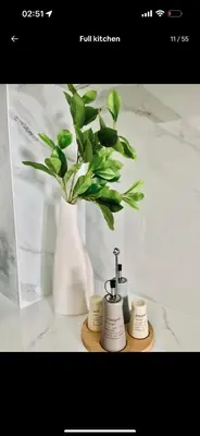 a white vase with a plant on a shelf at High Floor apartment in Jumeirah Village Circle in Dubai