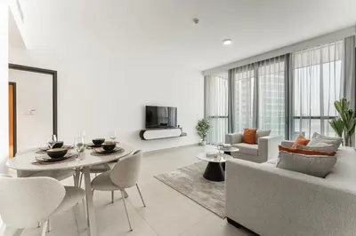 a white living room with a table and a couch at HAVN - 2 bedroom in Downtown Views Dubai in Dubai