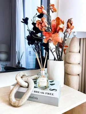 a book on a table with flowers and a candle at Stylish High-Floor Studio in Binghatti Azure! in Dubai
