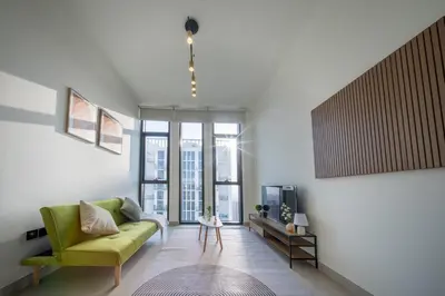 a living room with a green couch and a tv at Fully Furnished I Circle Mall I Sleeps 4 in Dubai