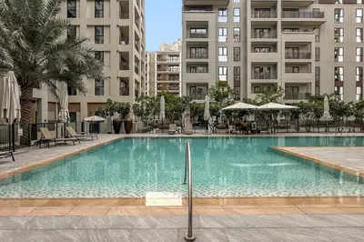 a swimming pool with chairs and umbrellas in a building at FIRST CLASS 1BR Creek Beach & Lagoon Escape in Dubai