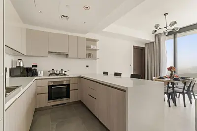 a kitchen with white cabinets and a table with chairs at FIRST CLASS 3BR Luxury Meets Tranquility in Dubai