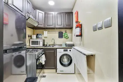 a small kitchen with a washing machine and a sink at Chic Studio in JVC near Butterfly and Miracle Garden in Dubai