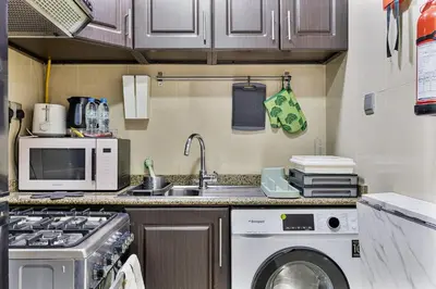 a kitchen with a sink and a washing machine at Chic Studio in JVC near Butterfly and Miracle Garden in Dubai