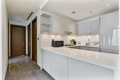 a kitchen with white cabinets and a counter top at Bookable 2 Bed Crest Sobha Hartland with Burj view in Dubai