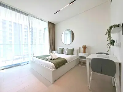 a white bedroom with a bed and a desk at Royalton - Modern JVC Studio Escape in Dubai