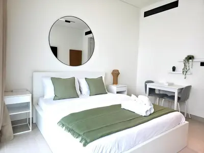 a bedroom with a bed with a mirror on the wall at Royalton - Modern JVC Studio Escape in Dubai