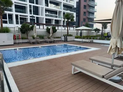 a swimming pool with chairs and umbrellas on a building at Azizi 205 Fully Furnished Apartment in Dubai