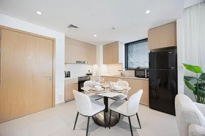 a kitchen with a table and chairs and a black refrigerator at Daniels 1BR at Bayshore 4 Creek Beach in Dubai