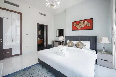 a white bedroom with a large white bed and a window at EasyGo - Elegant 2 Bedroom near Miracle Garden in Dubai
