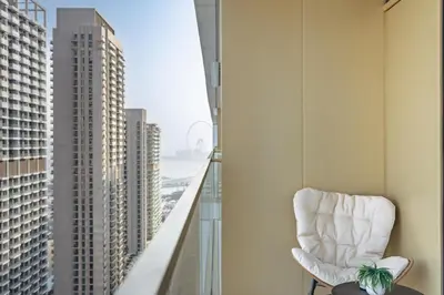 a white chair sitting on a balcony overlooking a city at Elegant 2BR with Sea View & Direct Beach Access in Dubai