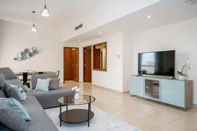 a living room with a couch and a flat screen tv at HiGuests - Fancy 1BR Apt With Aerial Marina Views in JBR in Dubai
