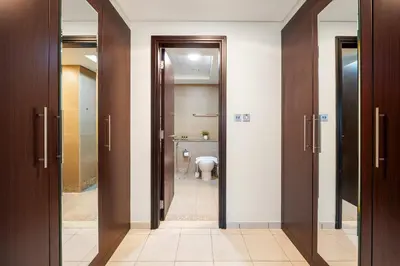 a bathroom with a toilet and a hallway with doors at Silkhaus Luxurious 1BR at Sky Gardens in DIFC in Dubai