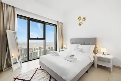a bedroom with a white bed and a large window at Downtown Comfort Spacious 1BR in Burj Royale in Dubai