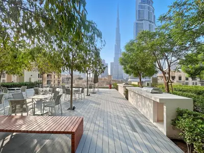 a wooden boardwalk with tables and chairs and a city skyline at Downtown Comfort Spacious 1BR in Burj Royale in Dubai