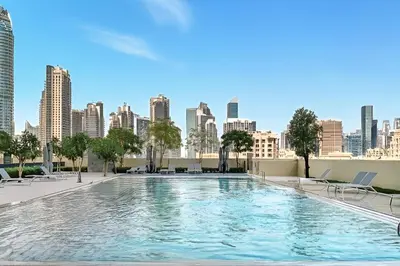 a large swimming pool with a city skyline in the background at Downtown Comfort Spacious 1BR in Burj Royale in Dubai