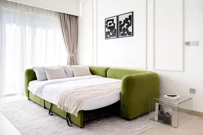 a green couch sitting in a living room at 1BR in Emaar Burj Royale - 1min walk to Fountain&Dubai Mall, Burj view Pool & gym in Dubai