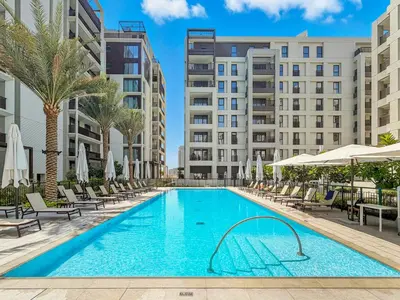 a swimming pool with chaise lounge chairs and buildings at New 3BD in Grove Creek Beach with Stunning View in Dubai