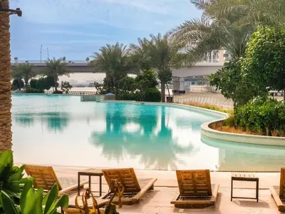 a swimming pool with chairs and a building at New 3BD in Grove Creek Beach with Stunning View in Dubai