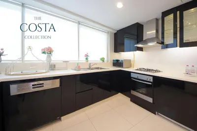 a kitchen with black cabinets and a sign that reads the costa collection at Water Edge 2BR - Panoramic 360 Canal View in Dubai