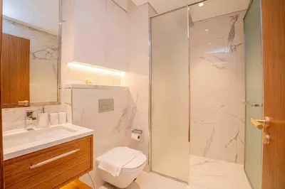 a bathroom with a shower and a toilet and a sink at Escape24 Stylish 2BR with Pool View at Azizi Riviera in Dubai