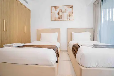 two beds in a small room with white walls at Escape24 Stylish 2BR with Pool View at Azizi Riviera in Dubai