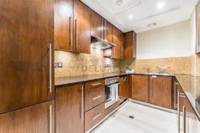 a kitchen with wooden cabinets and a sink at 1BR Near Burj Khalifa and Dubai Mall, Easy Access to Dubai Marina and Palm Jumeirah by Road or Metro, BLVD Walk, Downtown Dubai by Deluxe Holiday Homes in Dubai