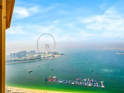 a pier in the water with a ferris wheel in the background at JBR's Luxury 2BDR with Dubai Eye, Palm & Marina Views - Direct Beach Access in Dubai