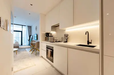a white kitchen with a sink and a stove at TRPS - Marquise Square, Business Bay - Burj Khalifa View, Spacious Studio, Fully Furnished in Dubai