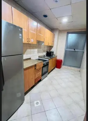 a kitchen with wooden cabinets and a stainless steel refrigerator at Furnished Partiton Room in Tecom Barsha Heights Near ICM Metro in Dubai